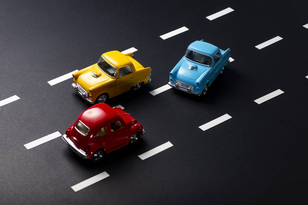 Niewłaściwe wyprzedzanie przez modele zabawek samochodów na drodze z paskami. - Zdjęcie, obraz