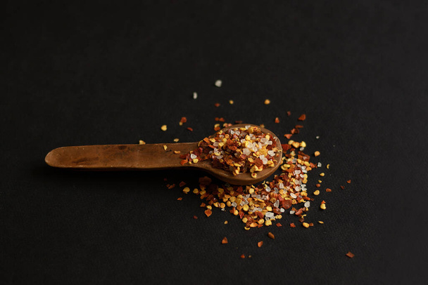 Coarse chilli on a clay spoon. Black background and minimalism. - 写真・画像