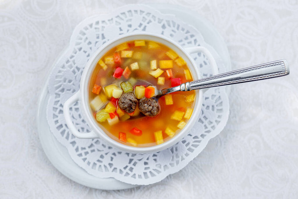 soupe de légumes aux boulettes de viande dans une assiette blanche sur une nappe blanche
 - Photo, image