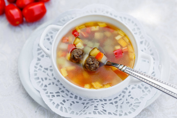 zupa warzywna z klopsikami w białej płytce na białym obrusie - Zdjęcie, obraz