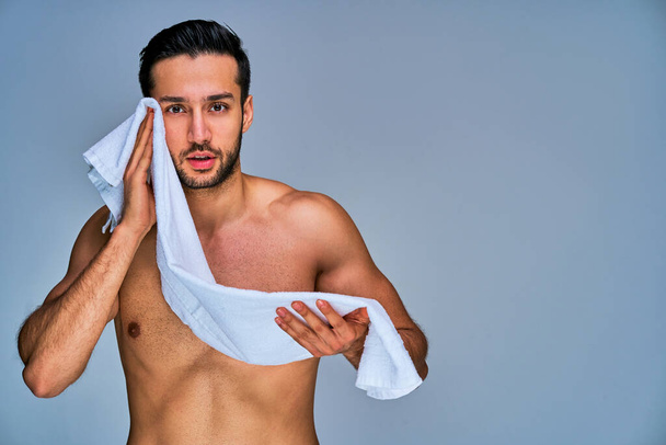 Tanned naked man with a white bath towel in hands - Foto, Imagem