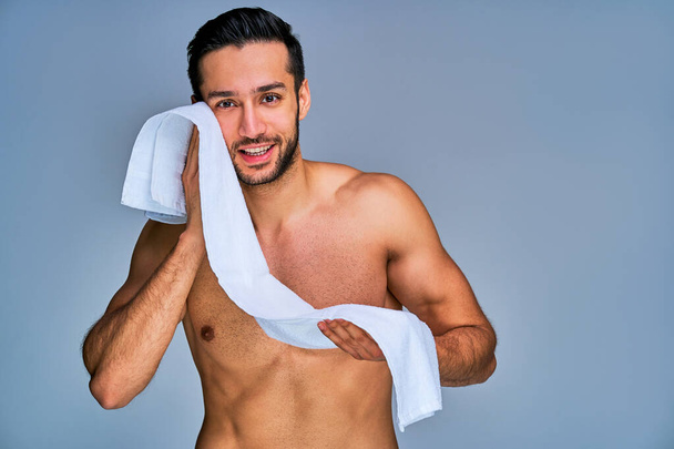 Happy tanned naked man with a white bath towel in hands - Foto, Imagem