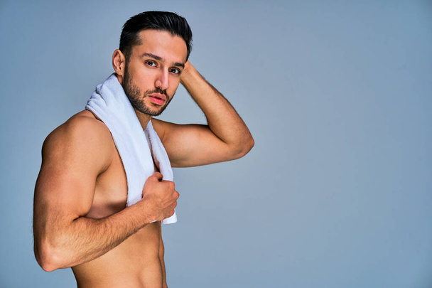 Handsome tanned naked man with a white bath towel posing on camera - Foto, immagini