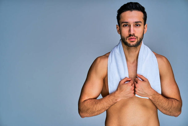 Well build guy holding a bath towel with by hands on neck posing - Fotografie, Obrázek