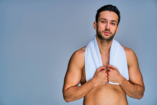 Well build guy holding a bath towel with by hands on neck posing - Foto, imagen