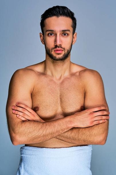 Hombre seguro con una barba negra en una toalla de baño blanca con los brazos cruzados
 - Foto, Imagen
