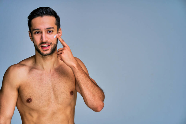 Happy man with black hair with cream spot on face looks at camera - Fotoğraf, Görsel