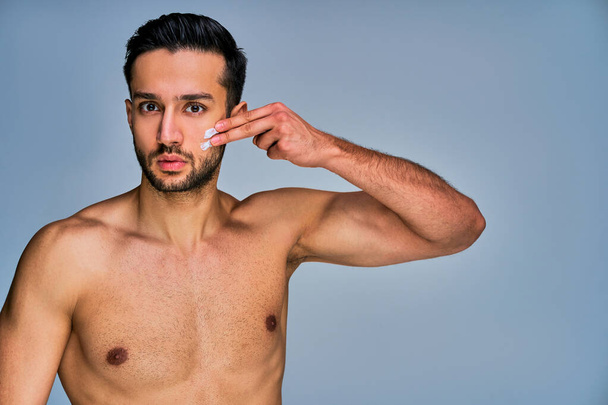 Serious man with black hair with cream spots on face posing at camera - Fotoğraf, Görsel