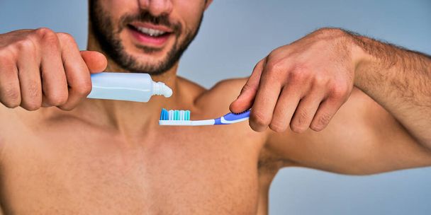 Male tanned hands with toothpaste and toothbrush in focus - Foto, immagini