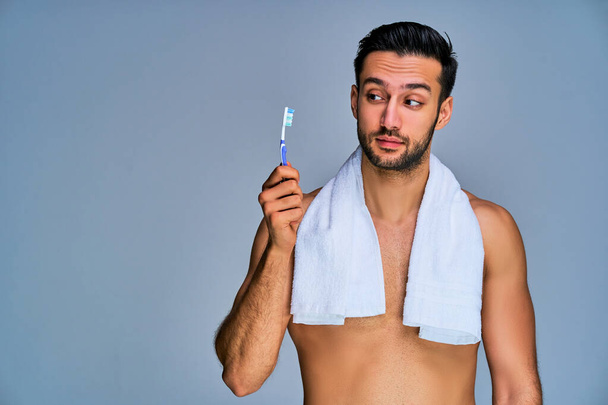 Tanned naked man with white bath towel on the neck with toothbrush - Фото, зображення