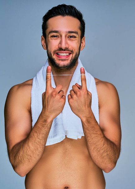 Happy man in white bath towel on the neck with dental floss on hands - Photo, image