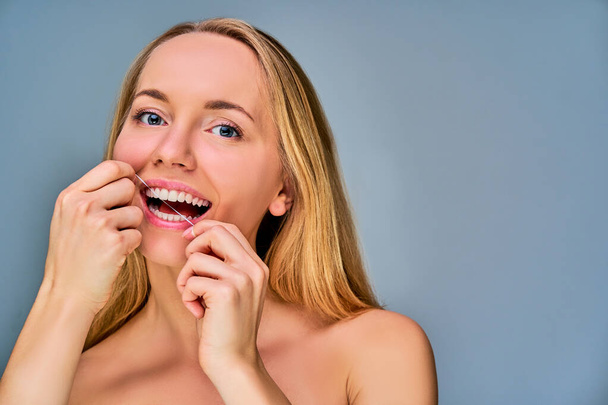 Woman with long blonde straight hair with dental floss in hands - Foto, Bild