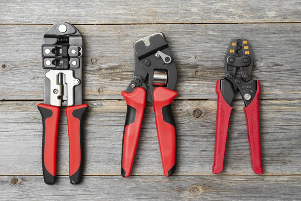 Tools for crimping stranded electrical wires. Crimping tools for electrician or Builder on a grey wooden background - Fotó, kép