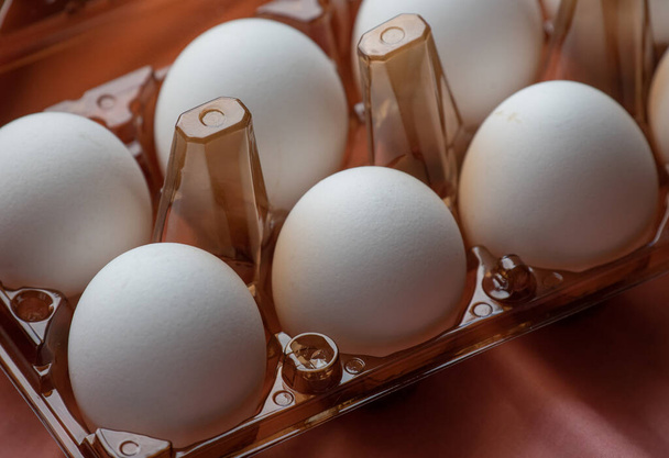 a természetes tojás fogalma. Egy tálca tojás, fehér és rózsaszín háttérrel. ökotálca herékkel. Minimalista trend, felülnézet. Tojásos tálca. Tojás, tyúktojás. Öko-termék, bio-étel. Húsvét. tojás, öko - Fotó, kép
