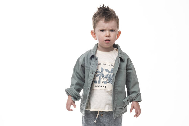 Un niño confuso parado sobre fondo blanco. Parece enfadado.
. - Foto, imagen