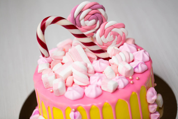 Childrens yellow cake with pink frosting, meringue and candies. - Фото, зображення