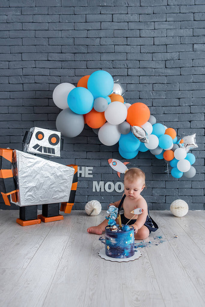 Little boy celebrates his first birthday. Space design with a robot and stars, many colorful balloons. - Fotografie, Obrázek
