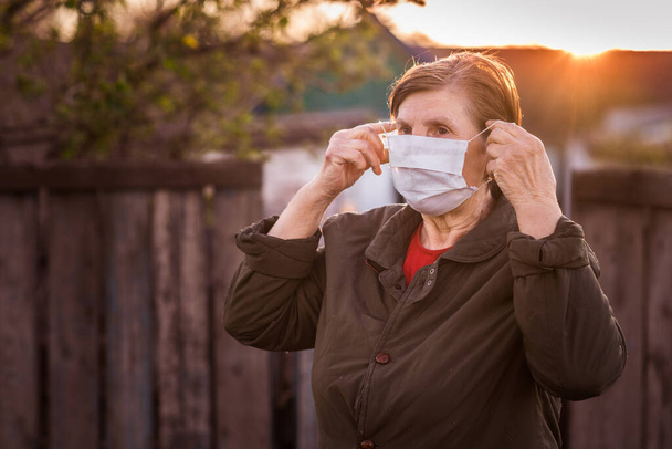 Старшая женщина в маске во время вспышки коронного вируса и гриппа. Защита от болезней и болезней. Хирургические маски для профилактики коронавируса. Больной пожилой пациент кашляет.
. - Фото, изображение