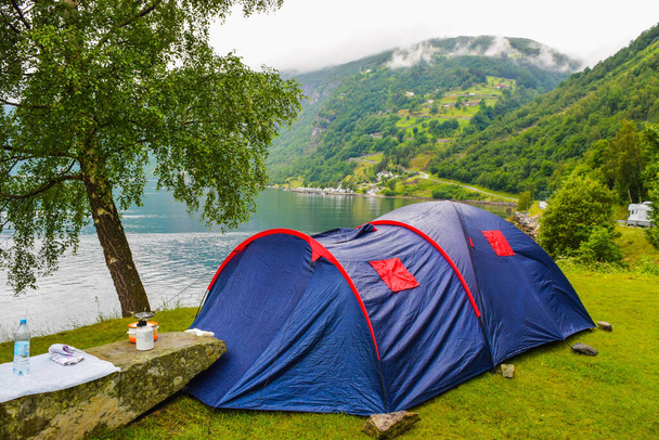 La tente touristique bleue est située près du village de Geiranger, sur la rive du Geirangerfjord, à l'arrière-plan de la route serpentine des Aigles, dans les montagnes. Voyage d'été en Norvège
. - Photo, image