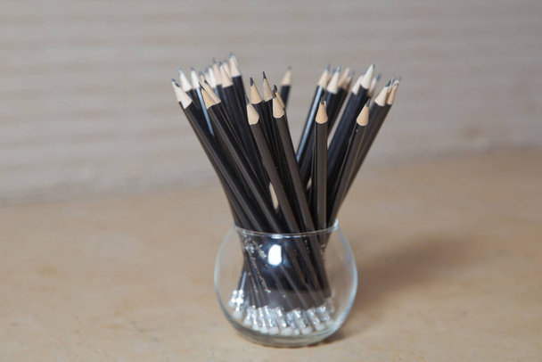black and wooden pencils in glass wooden table . pencils in black glass . minimalism concept - Foto, Imagem