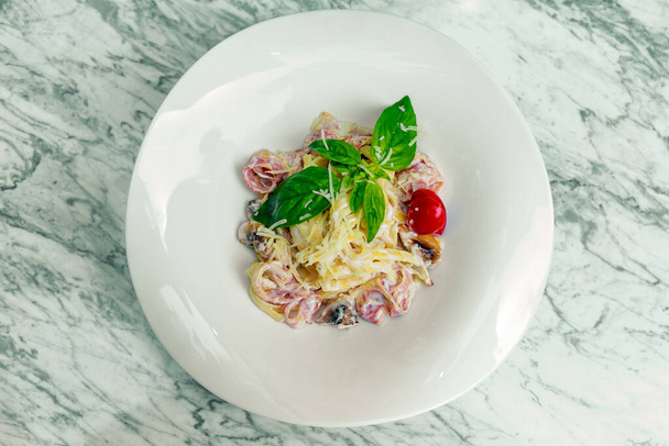 Italian pasta carbonara with bacon and mushrooms in a creamy sauce on a white plate - 写真・画像