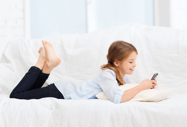 Smiling girl with smartphone at home - Foto, Bild
