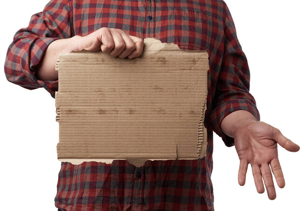 adult man in a red checkered crumpled shirt holds a piece of brown torn paper, place for an inscription, copy space - Photo, Image