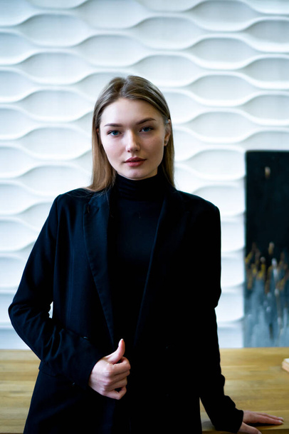 Business woman standing near the table in a black jacket - Zdjęcie, obraz