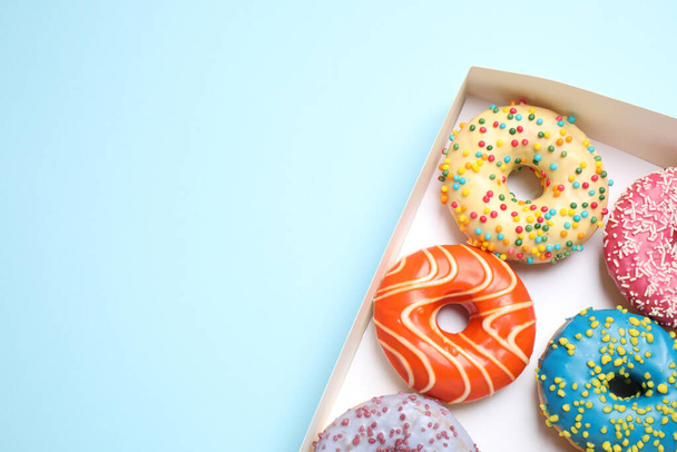 Delicious glazed donuts on light blue background, top view. Space for text - 写真・画像