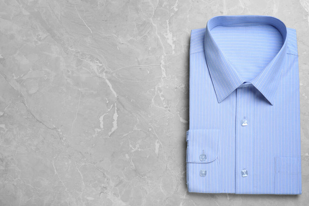 Stylish light blue shirt on grey marble table, top view with space for text. Dry-cleaning service - Foto, Imagen