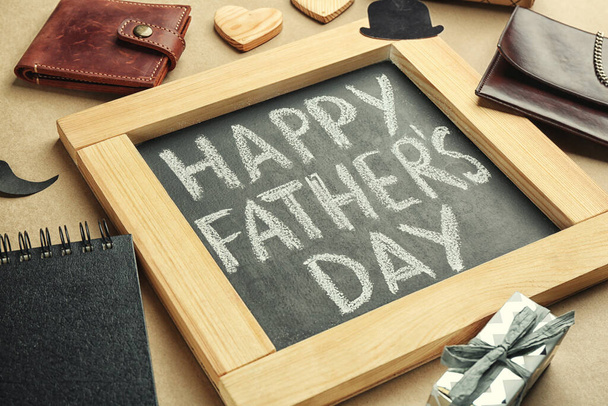 Chalkboard with phrase HAPPY FATHER'S DAY and male accessories on beige background, closeup - Valokuva, kuva