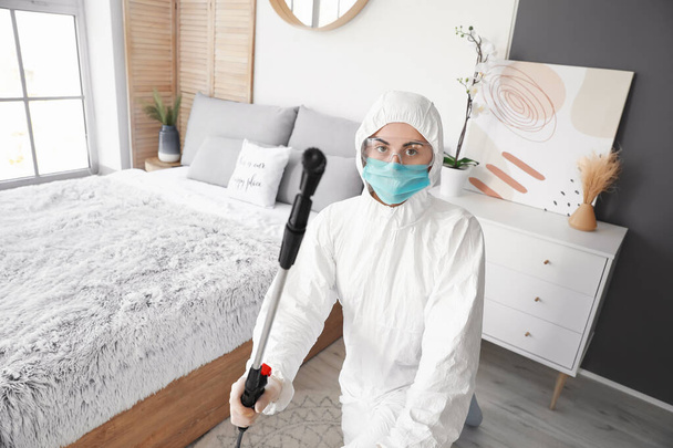 Trabajador en traje de riesgo biológico desinfectando casa - Foto, Imagen
