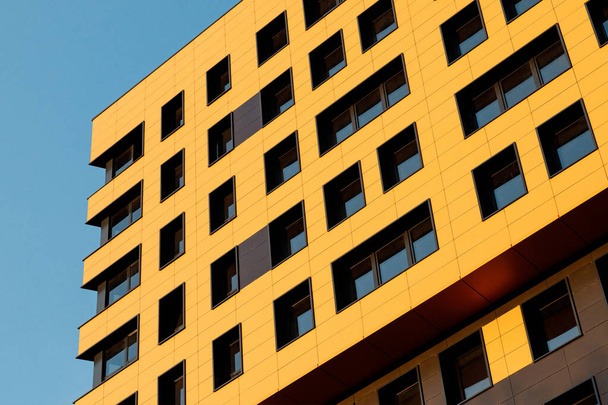 Żółta, nowoczesna, wentylowana fasada z oknami. Fragment nowego elitarnego budynku mieszkalnego lub kompleksu handlowego. Część nieruchomości miejskich. - Zdjęcie, obraz
