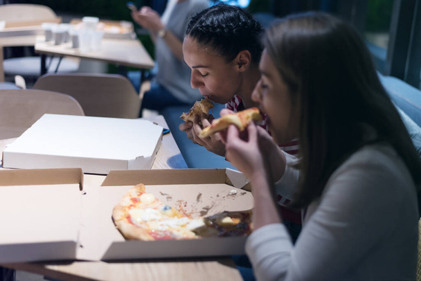 Belle jeune femme amies manger de la pizza et boire du cola tout en étant assis à l'intérieur expres restaurant tard dans la nuit. - Photo, image