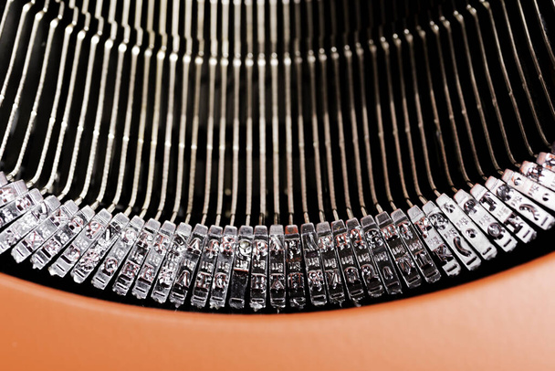 Um close-up ou macro tiro das barras de tipo de uma máquina de escrever manual estilo retro envolto em uma tampa superior vermelha articulada
. - Foto, Imagem