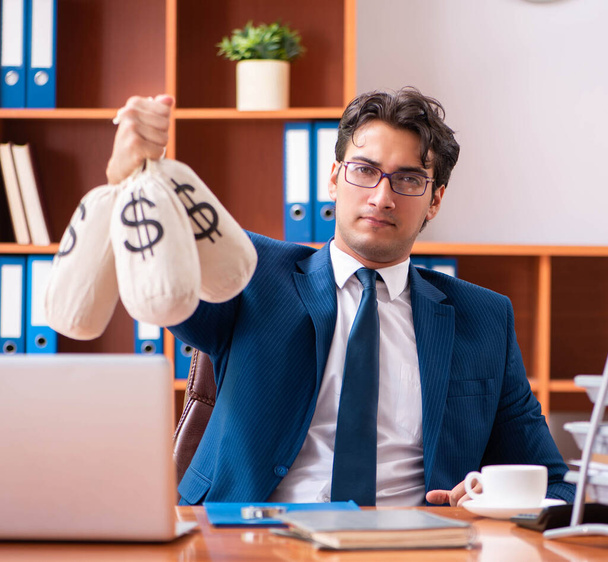 Молодой привлекательный бизнесмен работает в офисе - Фото, изображение