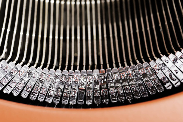 Zbliżenie lub ujęcie makro prętów typowych ręcznej maszyny do pisania w stylu retro, zamkniętej w zawiasowej czerwonej pokrywie górnej. - Zdjęcie, obraz