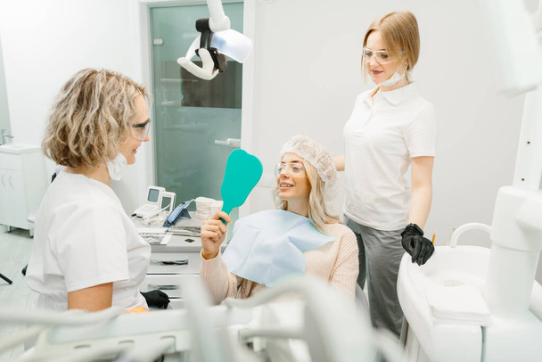 Dentista feminina em consultório odontológico conversando com paciente do sexo feminino e se preparando para o tratamento - Foto, Imagem