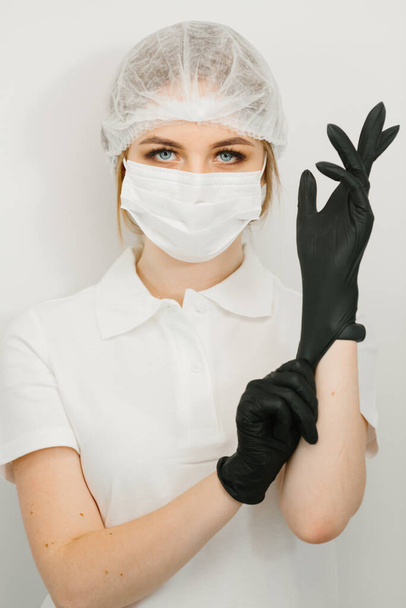 女性の歯医者はゴムかラテックスの手袋を置く。白地の肖像 - 写真・画像