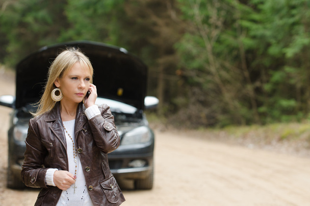 Woman at broken car with mobile phone - Foto, afbeelding