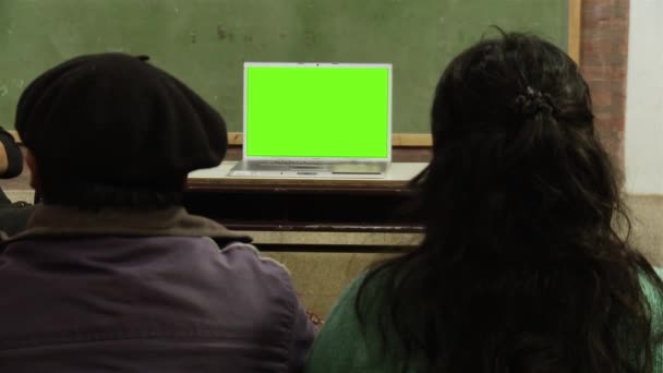 学校に座って、緑の画面でノートパソコンを見ている人。緑の画面を必要な映像や画像に置き換えることができます。After Effectsやその他のビデオ編集ソフトウェアでキーエフェクトを使用することができます(チュートリアルを確認してください) 。).  - 映像、動画