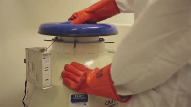 Egy női laboros nyitott egy folyékony nitrogén tartályt. Közelkép.  - Felvétel, videó