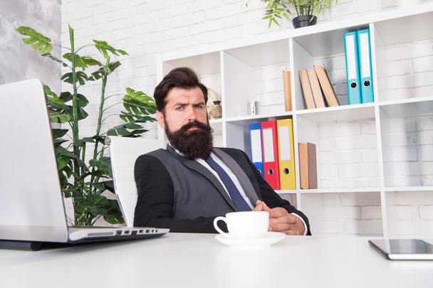 Office life is unthinkable without good coffee. Reception room. Respectable ceo. Man handsome boss sit in office drinking coffee. Comfy workspace. Bearded hipster formal suit relaxing with coffee - Fotoğraf, Görsel