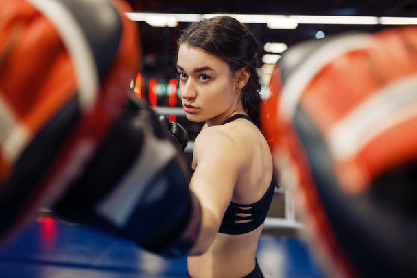 Woman in gloves boxing in the ring with trainer, box workout. Female boxers in gym, kickboxing sparring partners in sport club, punches practice - Fotografie, Obrázek