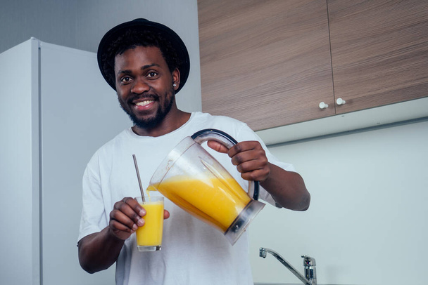 Good looking young african man making a smoothie for breakfast using a blender at home - Fotografie, Obrázek