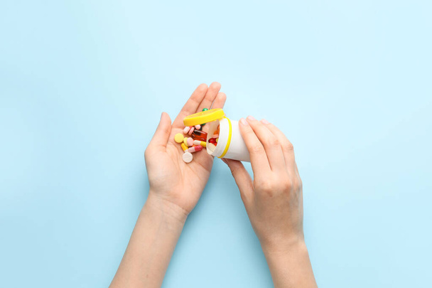 Female hands with bottle and pills on color background - Foto, imagen