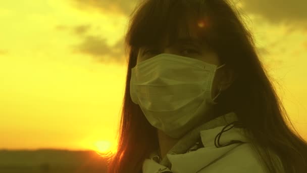 free woman wearing a protective medical mask in sunset light. close-up. Protection against viruses and bacteria. health and safety concept, coronavirus N1H1, virus protection. Pandemic coronavirus. - Footage, Video