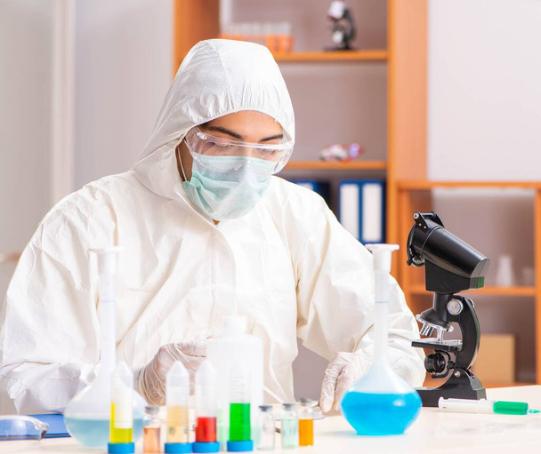 Молодий біохімік в захисному костюмі працює в лабораторії
 - Фото, зображення