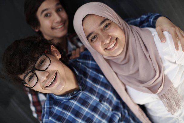 group of arab teens taking selfie photo on smart phone with black chalkboard in background - Photo, Image