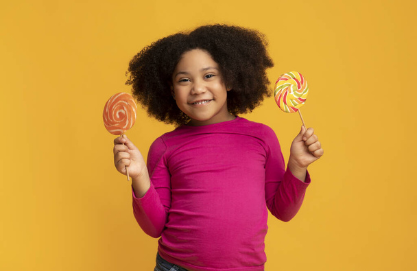 Two colourfull lollipops in hands of cute african american little girl - Foto, imagen